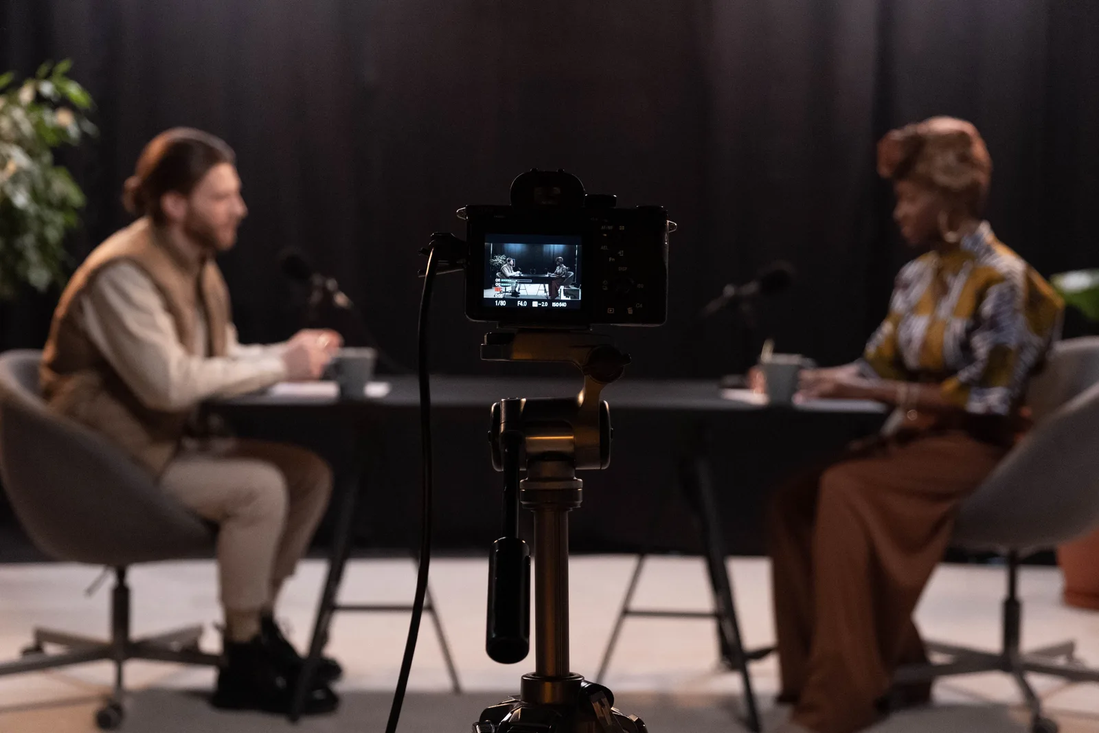 Two hosts recording a podcast in a studio setting with professional equipment.
