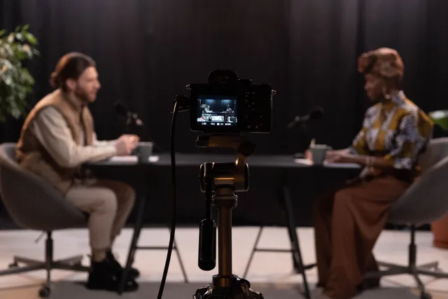 Two hosts recording a podcast in a studio setting with professional equipment. Accessible business video