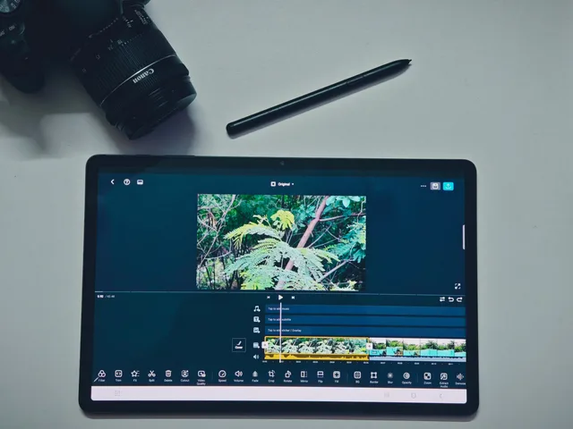 Tablet displaying video editing software with camera and stylus on a white background. Agreeing on revision rounds with a video supplier