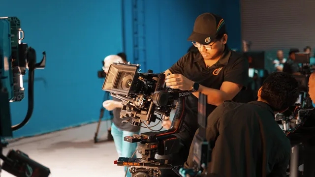 Film crew setting up professional camera equipment in a studio for shooting. Managing an outsourced video project