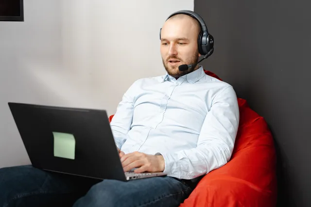 Call center agent working remotely on a laptop with headset and microphone for customer service. Video content strategy for business websites and owned channels